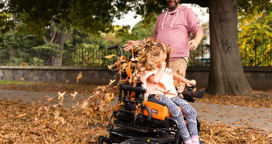 Ellie with a SPEX wheelchair playing happily with the leaves