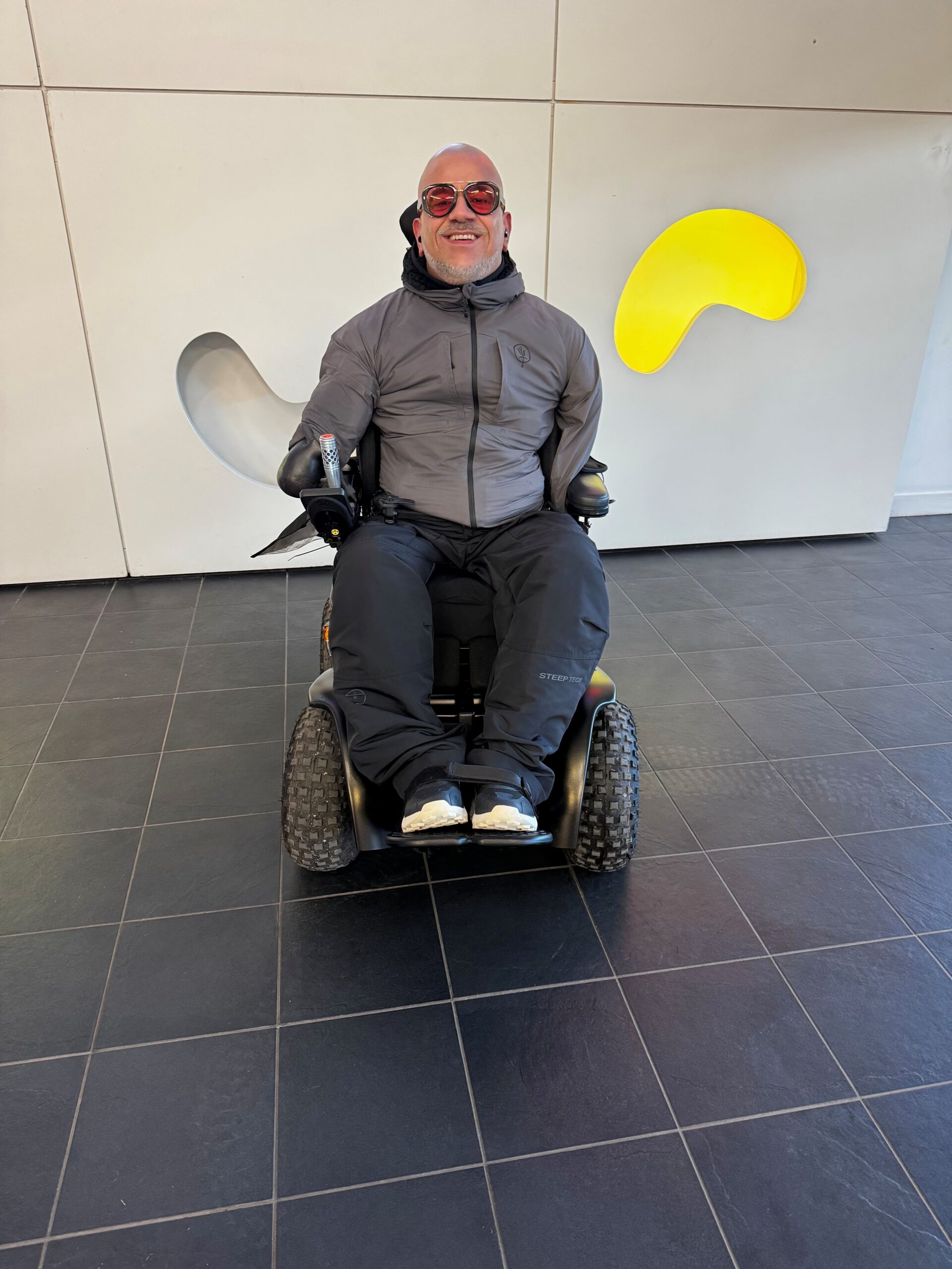 Chad, a Spex Manta back support user, smiling and seated upright in his wheelchair